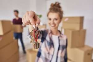 Woman holding a set of house keys with moving boxes behind her